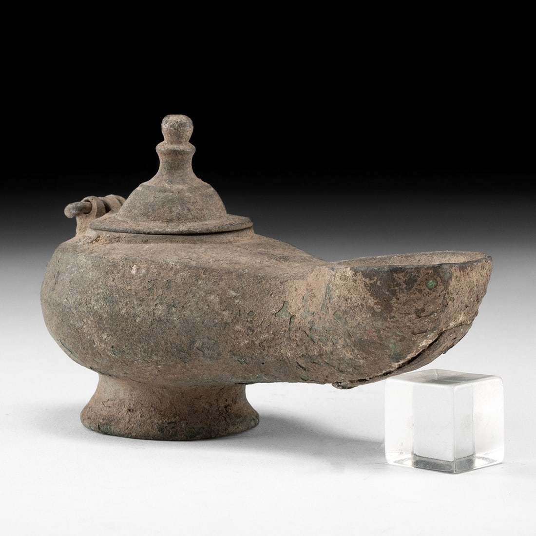Roman Leaded Copper Oil Lamp w/ Hinged Lid: Roman, Imperial period, ca. 1–300 CE. A leaded brass lamp of classic Roman form, its rounded body tapering forward into a long nozzle that opens in a broad, unblackened wick hole. The filling ap