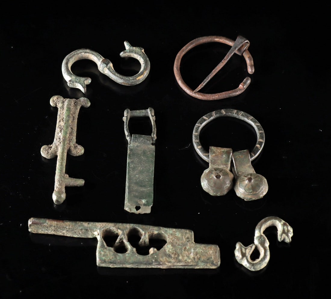 Roman–Medieval Bronze Artifacts | Snake Hooks, Penannular Brooch & Buckles: Ca. 1–1500 CE. Western Europe, Roman to Medieval periods, ca. 1st to 15th century CE. A collection of seven bronze and brass alloy artifacts including two S-shaped hooks with snake head terminal