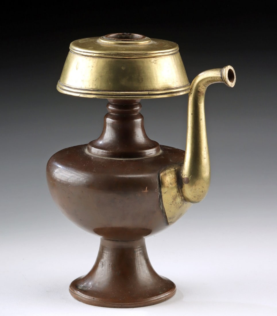 Buddhist Copper & Brass Bhumpa - Ritual Water Vase: Ca. 1700–1900 CE. Central Asia, Tibet, ca. 18th to 19th century CE. A ritual bhumpa (bumpa) water vessel crafted of copper with a brass spout and lid. Rising from a flared pedestal foot, the rou