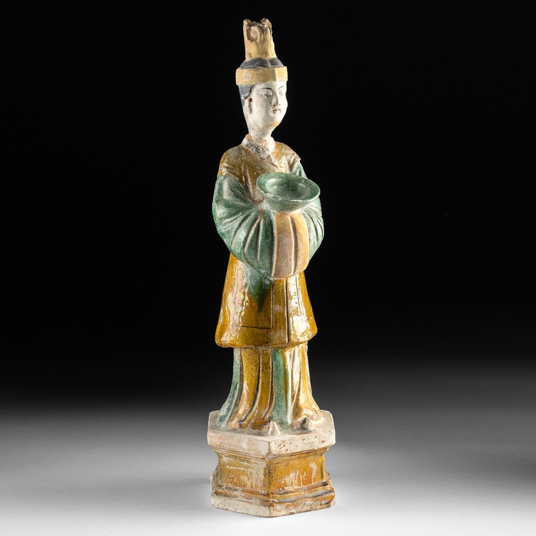 Chinese Ming Sancai Ceramic Funerary Mingqi w/ Offering Bowl: East Asia, China, Ming Dynasty, ca. 1368–1644 CE. East Asia, China, Ming Dynasty, ca. 1368 to 1644 CE. A mold-made pottery tomb attendant, or mingqi, coated in vibrant yellow, green, and amber s