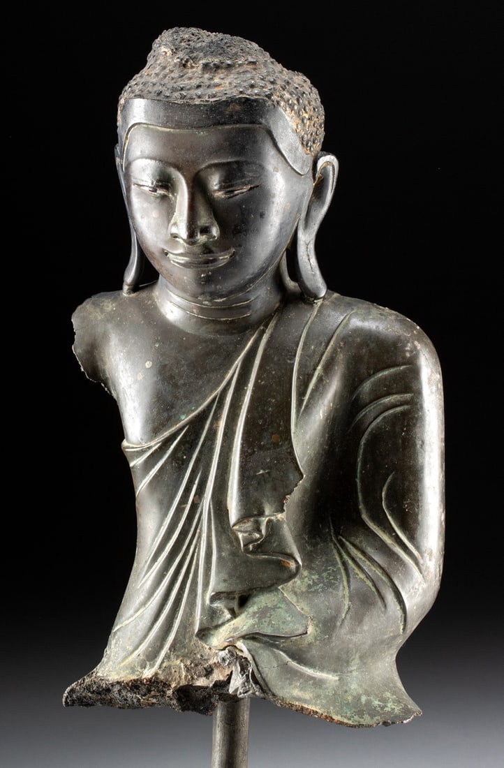 19th C. Burmese Bronze Buddha w/ Inlaid Enamel Eyes: Ca. 1800–1900 CE. Southeast Asia, Burma (Myanmar), ca. 19th century CE. A serene bronze sculpture of Buddha, depicted with a tranquil countenance of a gentle smile and downcast, enamel-inlaid ey