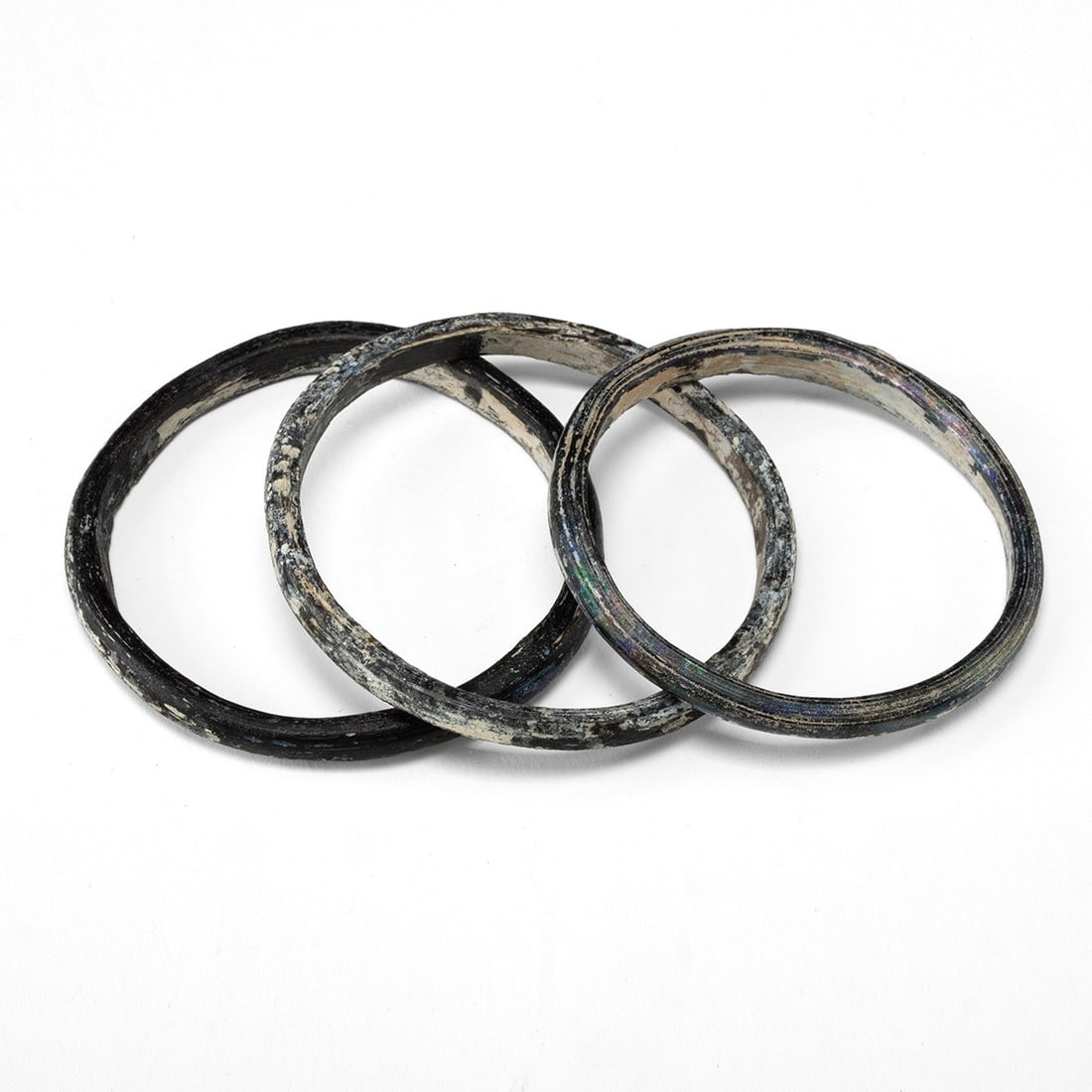 Three Ancient Roman Black Glass Bracelet Bangles: Roman, Imperial period, ca. 1–400 CE. Three ancient glass bangles of plain annular form, each drawn from a single rod of dark glass, bent to a circle and fused at the join, with rounded outer pr