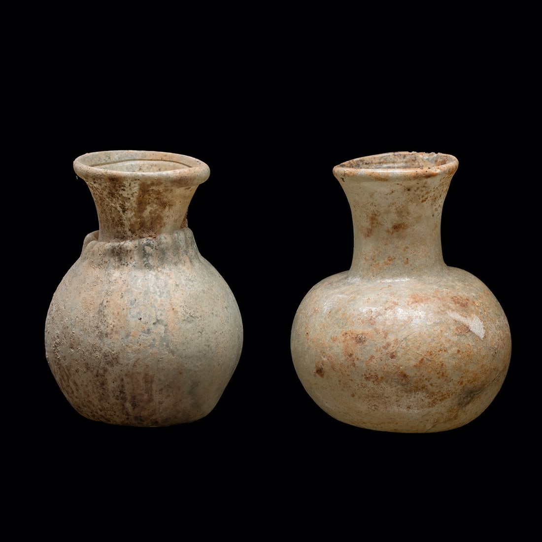 Pair of Roman Glass Jar - Globular Unguent Vessels: Roman, Imperial period, Eastern Mediterranean, ca. 100–400 CE. A pair of free-blown glass jars, each a squat globular body drawn up into a narrow cylindrical neck and finished with an outsplayed