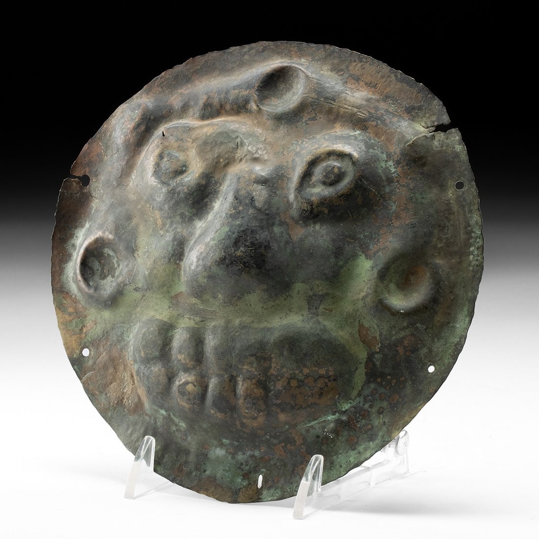 19th C. Himalayan Kirtimukha Repousse Maskette: Central Asia, Himalayas, Nepal or Tibet, ca. 1875–1960 CE. A grinning apotropaic face swells out of a thin brass disc, hammered from the reverse in repousse until nose, brow, and bulging eyes st