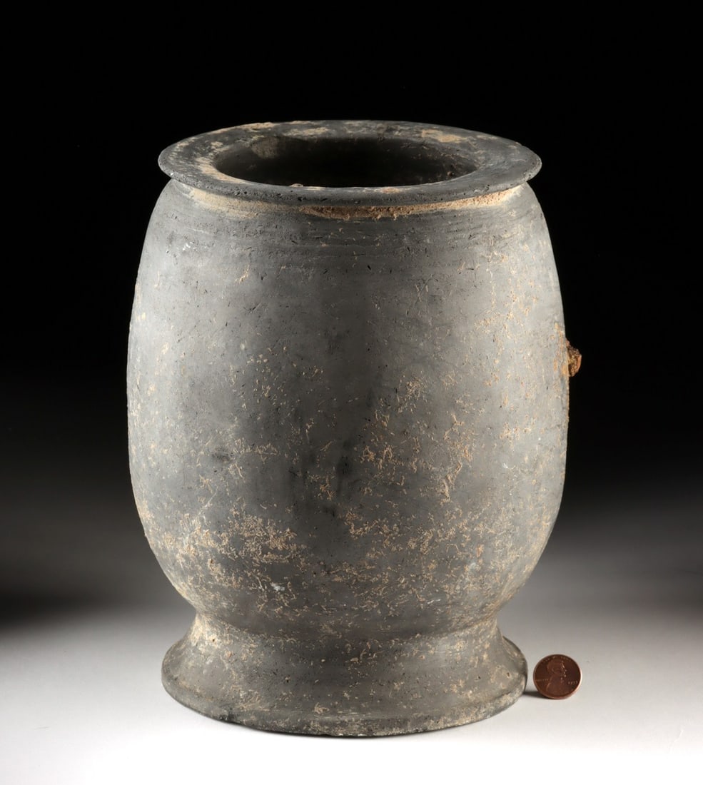 Korean Silla Grayware Stoneware Jar, Reduction-Fired: Ca. 526–726 CE. East Asia, Korea, Silla Kingdom. This reduction-fired gray to near-black stoneware jar swells from a broad splayed foot into a rounded body and finishes in a short neck with a cr