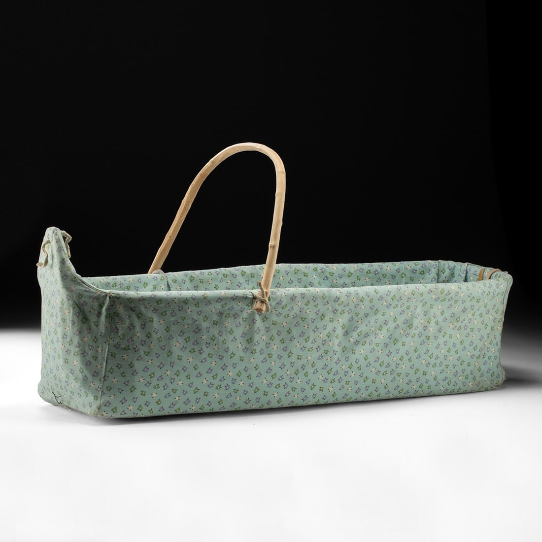 Native American Cradleboard w/ Bent Willow Bow & Calico Cover: Native American, likely Southwest or Great Basin, ca. 1975–1988 CE. A cradleboard built for an actual infant rather than a shelf, its elongated boat-shaped body rising from a rigid foundation, l
