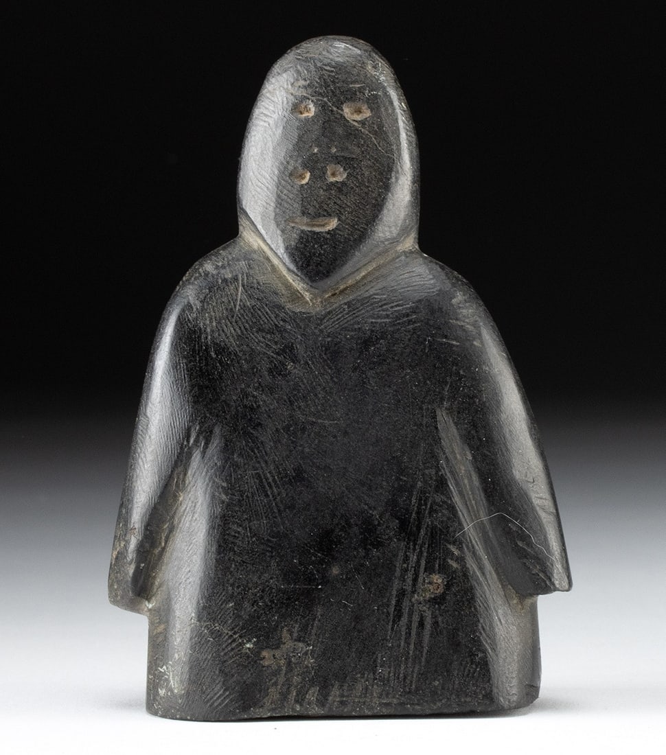 Inuit Soapstone Figural Carving, Signed in Inuktitut: Ca. 1934–1967 CE. First Nations, Canada, northwestern Quebec, ca. mid to late 20th century CE. A hand-carved soapstone figure with a compact, simplified form and a thick torso, with arms held cl