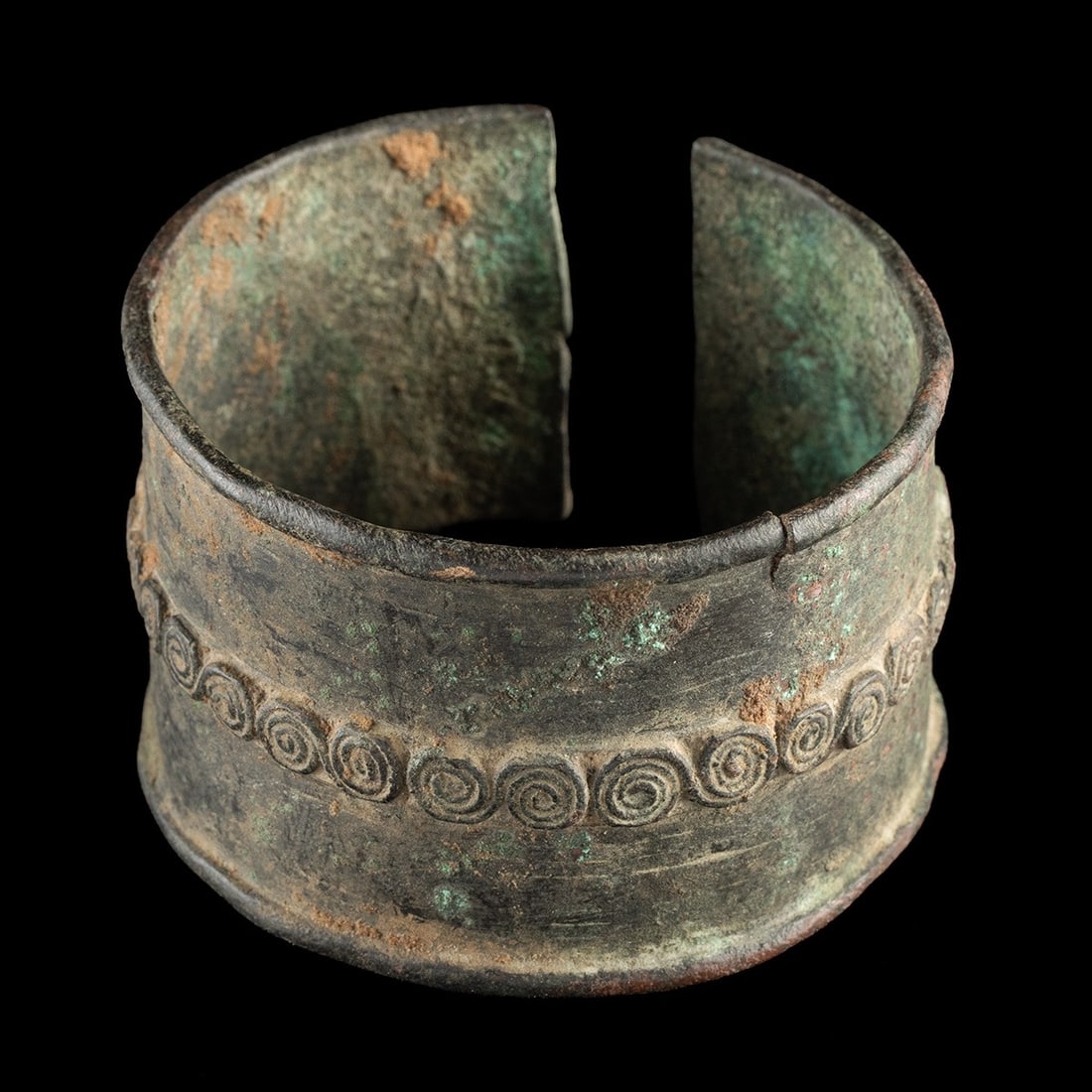19th C. West African Sahelian Leaded Brass Armlet - Spiral Coil Motif: West Africa, Sahel region, ca. 1800–1935 CE. A broad cuff of leaded brass, lost-wax cast in a single open-ended band whose flaring lip and gently waisted profile were designed to grip the forear