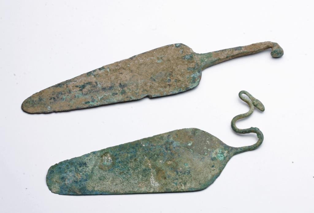 Lot of 2 Luristan Bronze Spears: Near East, Luristan, ca. 1000 BCE. Two bronze spear heads with intact tangs. First spear is a rare spear with right angled tang with wave patter that curls back at end. Bronze is especially thin and d