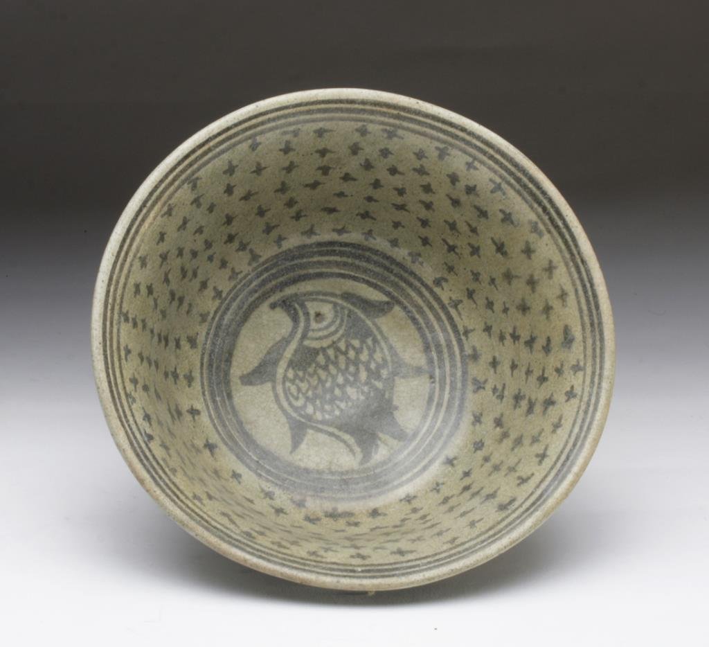South East Asian Glazed Fish Bowl: South East Asia, ca. 10th - 12th century CE. A glazed pottery bowl with fish design. Flared bowl sits on raised pedestal, is slipped in a light green glaze, and decorated with linear and geometric des