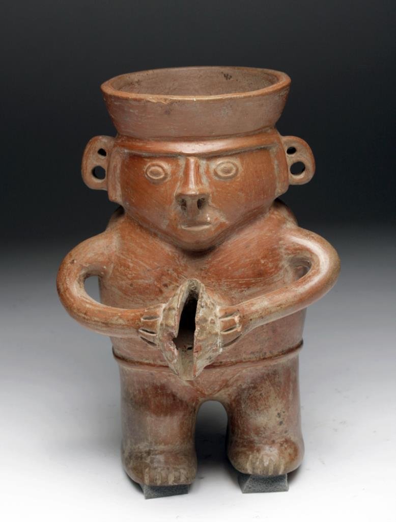 Fine Inca Human Form Jar - Standing Male: Central Peru, Ca 1300 to 1500 CE. A very attractive redware pottery jar in the form of a standing male, with triangular face, large round eyes, double-perfed ears, holding a spondylus shell - possibly