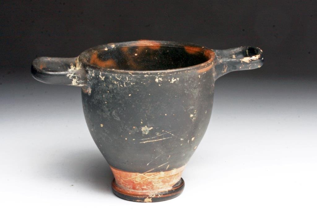 Greek Apulian Bi-Chrome Skyphos: Magna Graecia, Apulian Culture, ca. 4th century BCE. A wonderfully crafted cup of classic Greek form. Twin handles on either side of the rim, a low platform that gently tapers out into the chalice. Sl