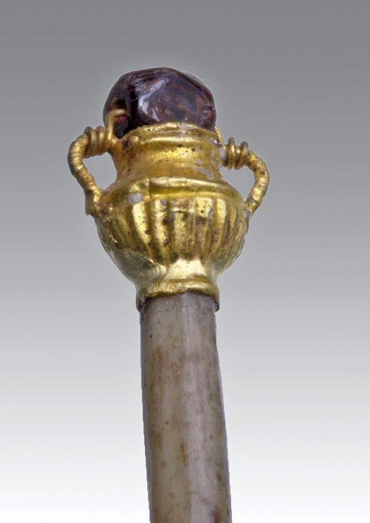 Ivory Hairpin with Ancient Roman Gold Amphora End: Rome, ca. 1st - 4th century CE. Delicate gold amphora mounted on the end of an ivory hair pin (modern) with a purple gemstone suspended above the amphora. Ribbing along base of amphora. 4-7/8"L. Prove