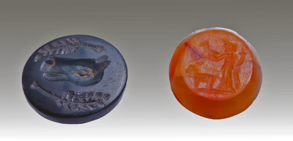Lot of 2 Near East Stone Intaglio Pendants: Near East, Possibly Sassanian, ca. 300 CE. Red stone with carved man holding hawk in hand with goat standing in front of him. Green stone has carved donkey head with pieces of grain on either side. Bo