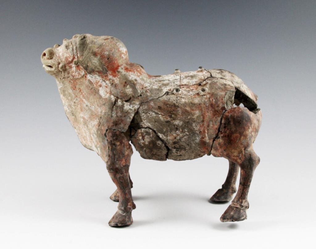 Chinese Northern Qi Dynasty Earthenware Ox / Bull: From the ancient Qi Dynasty of China, circa 550 - 577 CE. Measures approximately 8" long x ~ 6-1/2" tall. This fired earthenware animal figure depicts an Ox or bull. This figure would have been placed