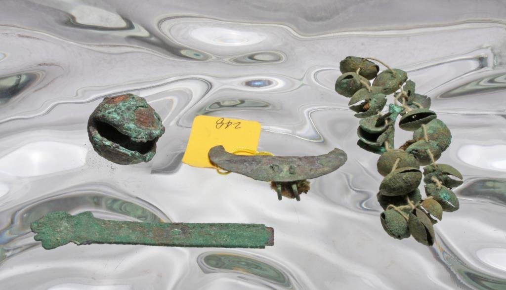 Ancient Pre-Columbian Peruvian Copper Group Lot: Peruvian, likely Inca, ca. 1000-1500 CE. Group of copper pieces including a strand of hammered copper bells and tweezer fragments, a large and weighty bell, tumi fragment, and a bird-like pendant. Stu