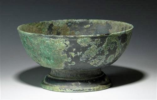 Khmer Bronze Footed Bowl: Khmer, Cambodia, Ca 1200 CE. Of circular shape / simple decoration, solid bronze vessel sits upon a wide raised footed base. 2"H x 3-7/8"D. Provenance: Ex-Private Houston, TX Collection. All items in 