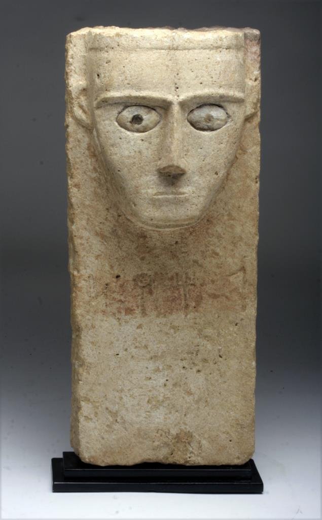 South Arabian Limestone Stele: South Arabian, Yemen, ca 2nd century BCE - 2nd century CE. A large dedicatory limestone carving of man with stylized bearded head, inlaid eyes, and Qatabanite inscription. A very striking piece! Custo