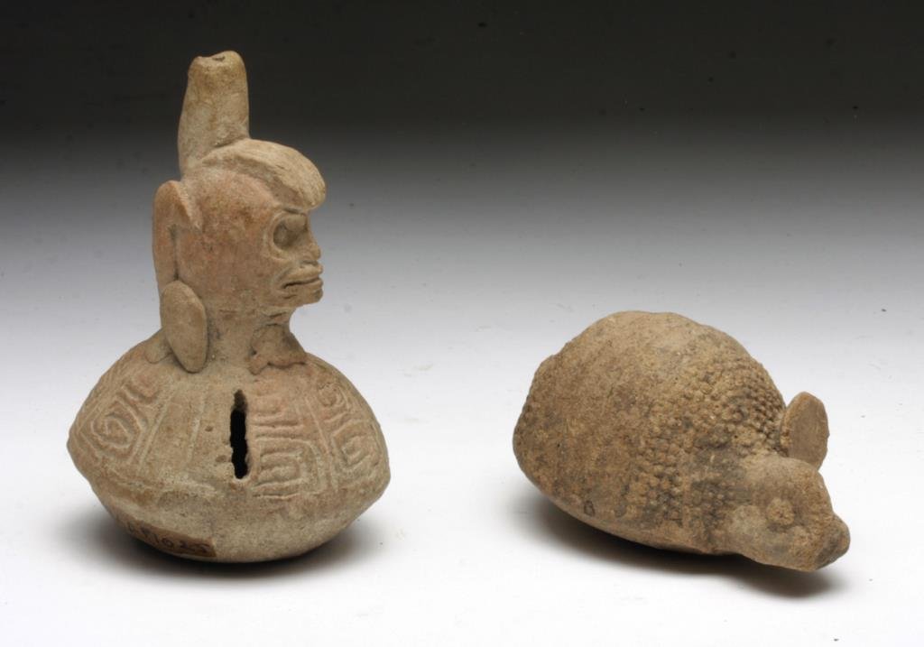 Lot of 2 Mayan Flutes / Rattles: Pre-Columbian, Mayan Territories, ca. 600-900 CE. These pottery figurines function as both flutes and rattles, one taking the form of an elaborately adorned skull, the other an endearing armadillo. Bo