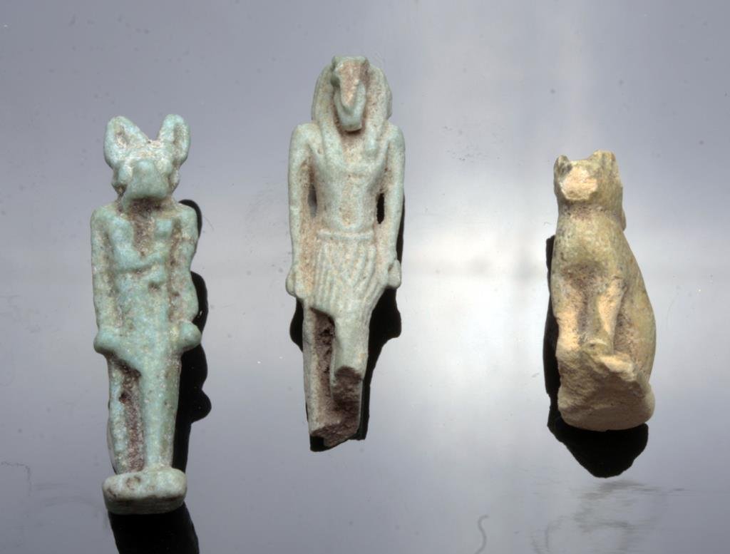 Lot of 3 Egyptian Faience Figures: Egypt, Late Period - Ptolemaic, ca. 500 - 100 BCE. A set of three faience figures, a light blue striding Anubis, a green/yellow seated Bastet cat figure, and what appears to be a striding king with pr