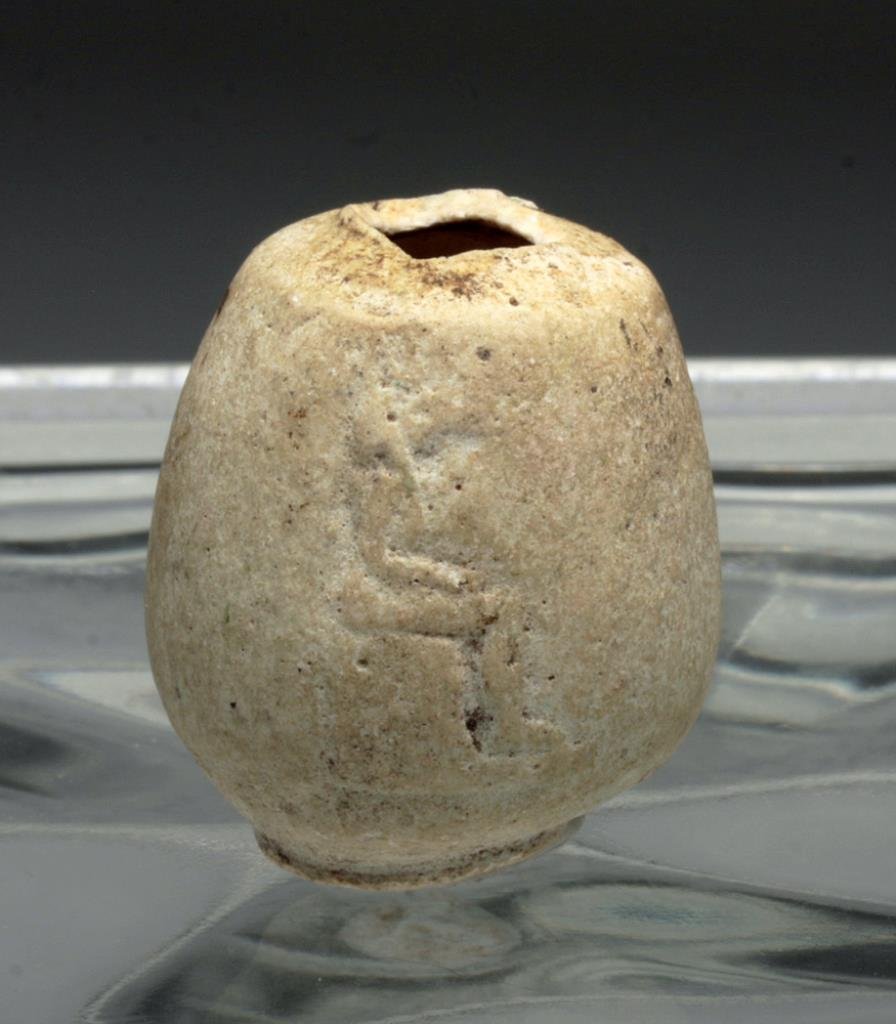 Rare Egyptian Faience Cosmetic Jar - Anubis: Egypt, Late Dynastic, Ca 662 to 300 BCE. Oblong cosmetic jar in eggshell thin faience, with small ringed foot and once with flat rim, now missing, decorated with single image of a seated Anubis in low