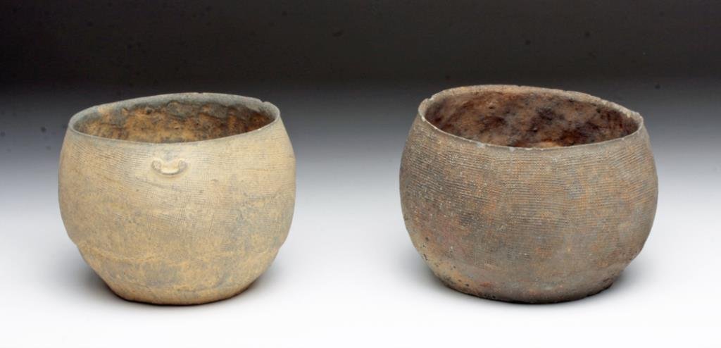 Lot of 2 Chinese Warring States Greyware Bowls: China, Warring States Period, ca. 475 to 221 BCE. A lovely pair of small terracotta grey-ware vessels, each with impressed textile texture around sides, one with small faux-handles on either side. Fla
