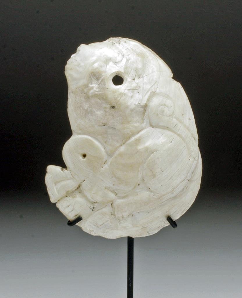 Large Jamacoaque Carved Shell Pendant: Pre-Columbian, Ecuador, ca 500 to 800 CE. This Jama Coaque pendant is carved from a gorgeous white abalone shell or thin segment of giant clam shell. Custom stand. Shell itself measures 3-3/4"H x 3 1/