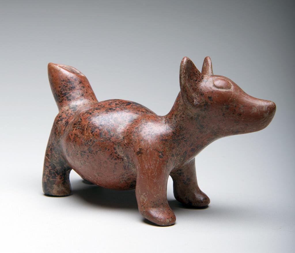 Pre-Columbian Colima Dog Effigy: Colima, West Mexico, ca. 500 BCE – 500 CE. Redware pottery figure of a dog standing on all fours. Typical plump belly. Liberal manganese deposits on surface. 6"L x 4"H. Provenance: Ex-prominent Holl