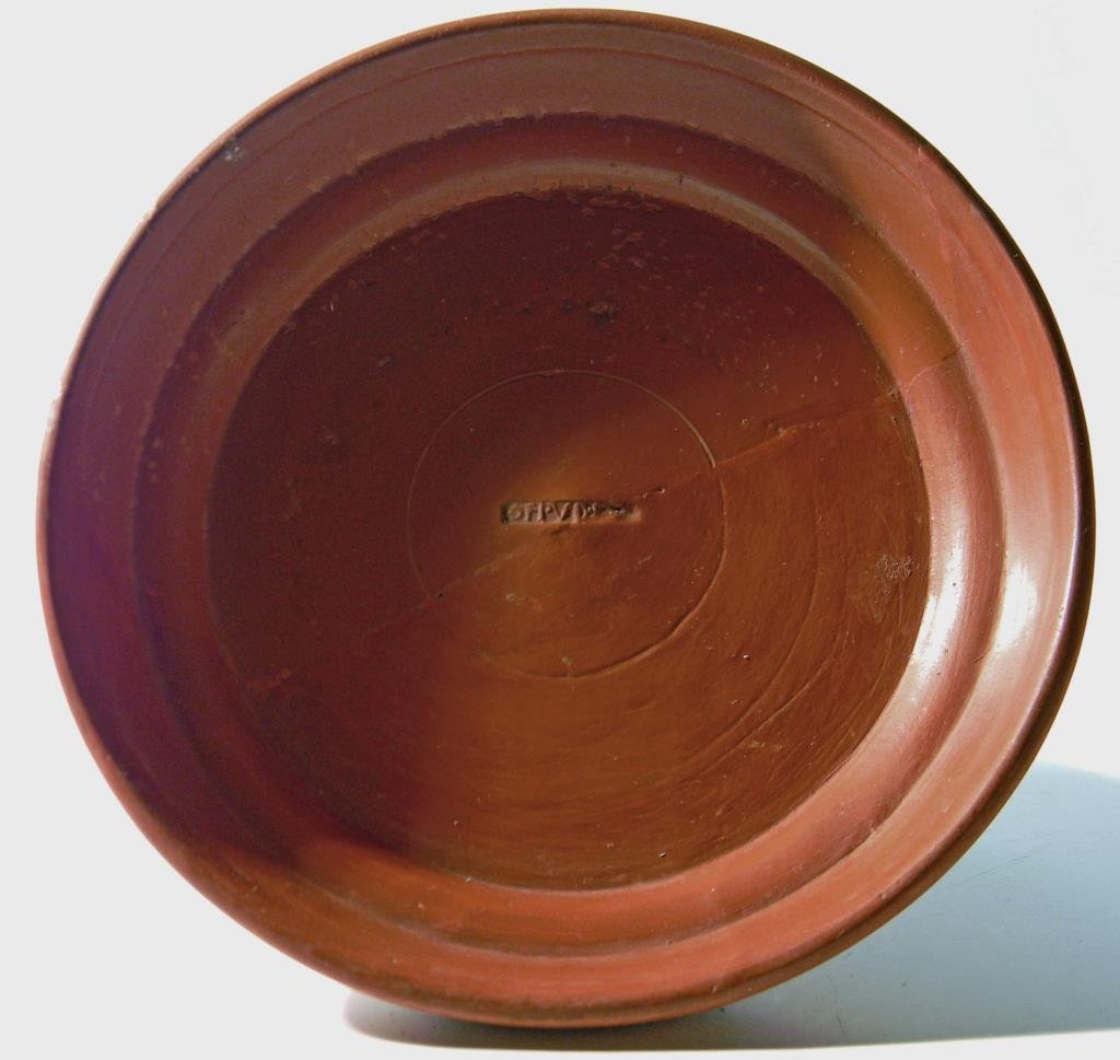 Roman Terra Sigillata Shallow Bowl, Maker's Mark: Roman, North Africa, ca. 1st century CE. An ancient redware pottery shallow dish bearing a potter's stamp in the tondo, OF PVDEN, and a graffito on the exterior, PA. 5-3/4"D (14.5 cm). Provenance: For