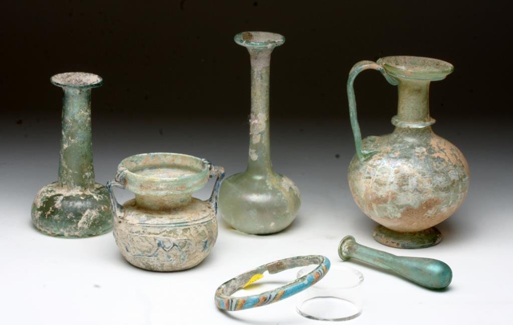 Lot of 6 Roman and Islamic Glass Vessels: Rome, ca. 1st - 4th century CE. A collection of six pieces of glass, a highly iridescent small tear vial (4"H. Stable stress crack), two tall green glass flasks with flared rims (5-1/4"H intact; 6-3/4