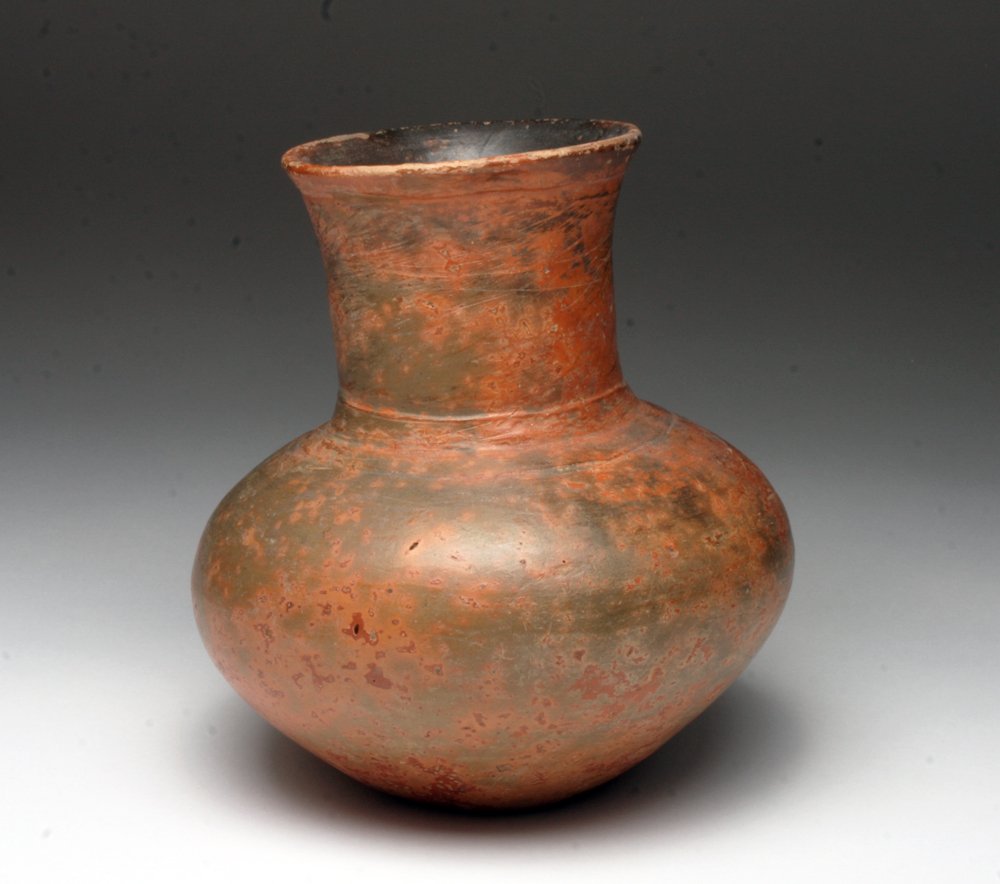 Pre-Columbian Mayan Plumbate Bottle: Mayan Territories, ca. Terracotta pouring vessel with red finish. Bulbous body with raised spout. 7"H Provenance: Ex-prominent TX collection. All items in this auction are legal to buy/sell under U.S.