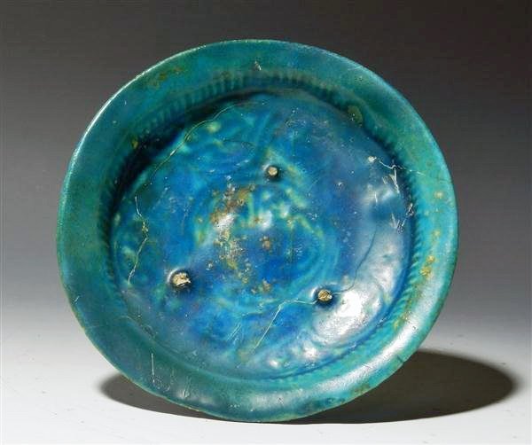 Islamic Blue Glazed Terracotta Dish: Middle East, Ca. 10th Century CE. Pottery low dish with a bluish green slip, detailed floral design under slip with hatching along sides. Bottom is not glazed as is custom with such vessels, face of d