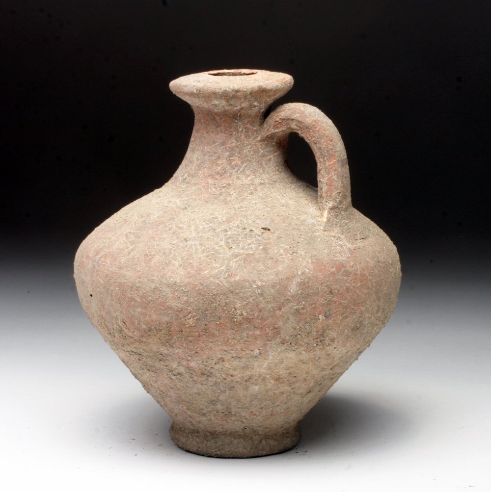 Roman Redware Jug: Rome, ca. 2nd - 3rd century CE. A wheel made redware jug with tulip shaped body, small pedestal, strap handle, and flared rim. 5-1/2"H. Provenance: Ex-Private Colorado Springs, CO Collection. All item