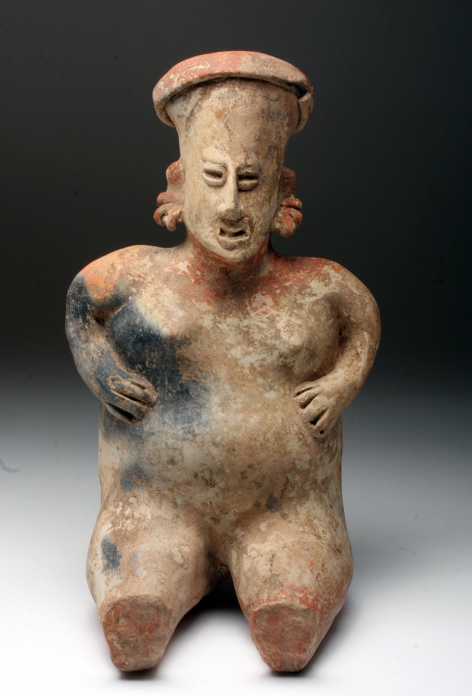 Pre-Columbian Jalisco Seated Female: Western Mexico, Jalisco Region, Ca 200 BCE to 200 CE. Hollow pottery figure of a seated female, hands held to her slightly swollen (pregnant) belly, shown nude save 3 earrings per ear and turban style