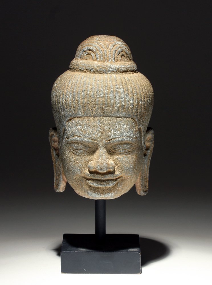 Khmer Carved Stone Buddha Head: Cambodia, Ca. 12th -14th Century CE. Carved sandstone with incised details of hair, face, hat, and ears. Mounted on a museum quality stand. 6"H. Provenance: Ex-private San Diego, CA Collection. All it