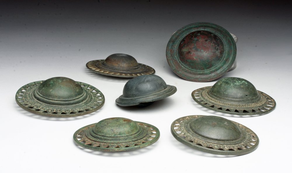 Lot of 7 Khmer Bronze Belt Buckles: Cambodia, Khmer Empire, ca. 12th - 14th century CE. A set of seven cast bronze domed belt buckles, most with geometric designs surrounding dome. Loops and clasps on rear make these usable today! 2-1/2