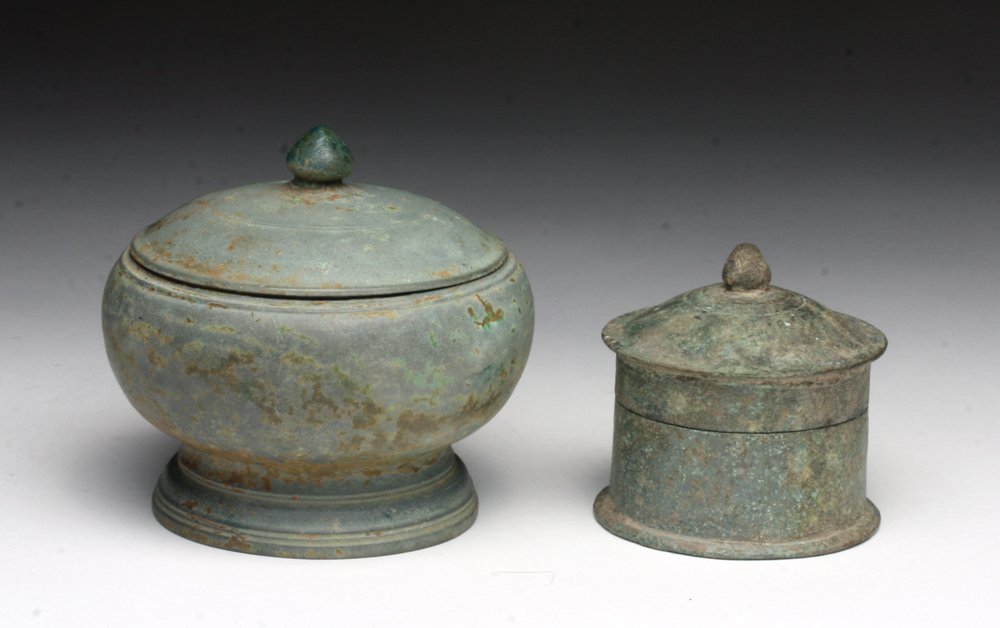 Lot of 2 Khmer Bronze Pyxii: Cambodia, Khmer Empire, ca. 12th - 14th century CE. Two cast bronze vessels, each with removable lids with lotus handles, likely used as lime pots. Larger pyxis of very delicate bronze. 2-1/2" & 3-1/2