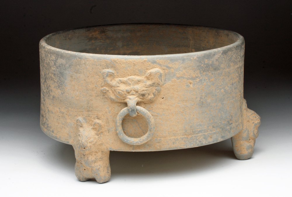 Chinese Han Dynasty Greyware Tripod Vessel: Chinese, Han Dynasty, ca. 206 BCE - 220 CE. A greyware tripod offering vessel with taotie masks holding ring handles and rabbit feet. 9-1/4"D x 5-3/4"H. Provenance: Ex-private San Diego, CA Collection