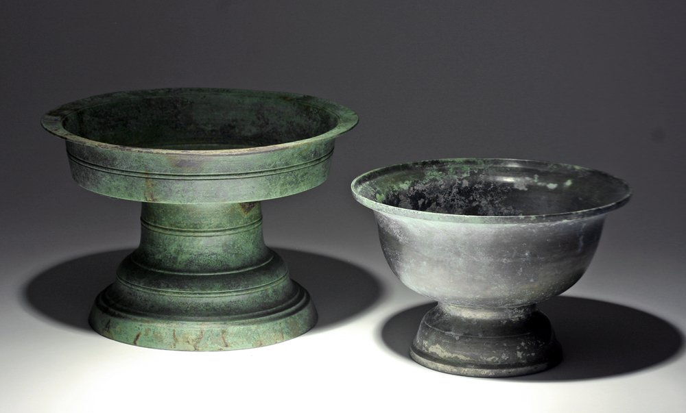 Lot of 2 Khmer Bronze Offering Dishes: Cambodia, Khmer Empire, ca. 12th - 14th century CE. Two cast bronze pedestal dishes, likely serving a purpose for offerings. Each with flared bronze pedestal, and bowl mounted on top. Both exhibit a b