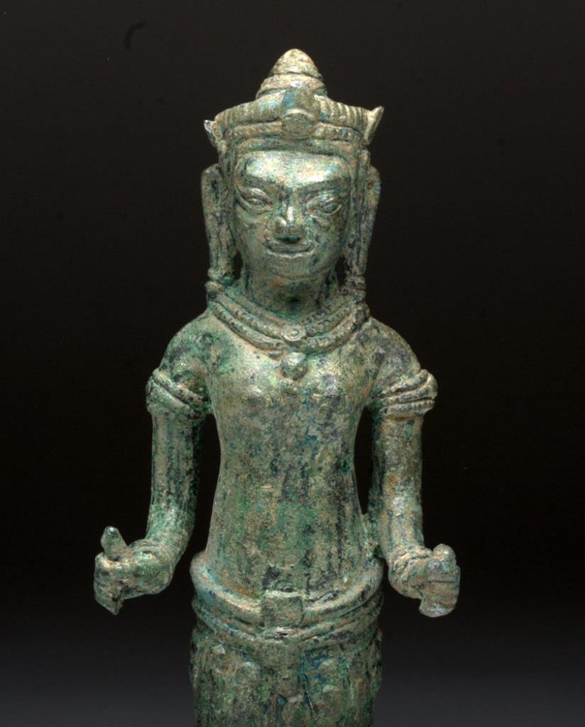 Khmer Bronze Figure of Parvati (Uma): Cambodia, Angkor Period, Ca 13th century CE. Bronze figure, Bayon Style, shown standing upon an integral plinth, depicts the goddess standing straight, holding a rolled up scroll in her left hand and 