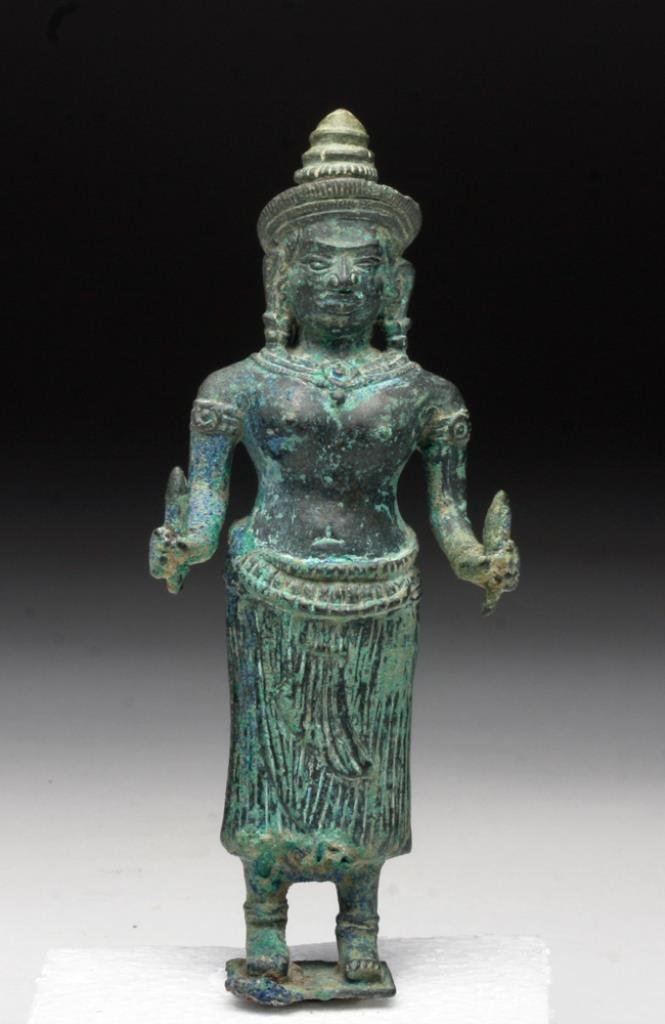 Khmer Bronze Figure of Goddess (Uma): Cambodia, Angkor Period, Ca 12th to 13th century CE. Bronze figrue shown standing upon a square base, insertion tang beneath, goddess standing straight, holding a rolled up scroll in her left hand and
