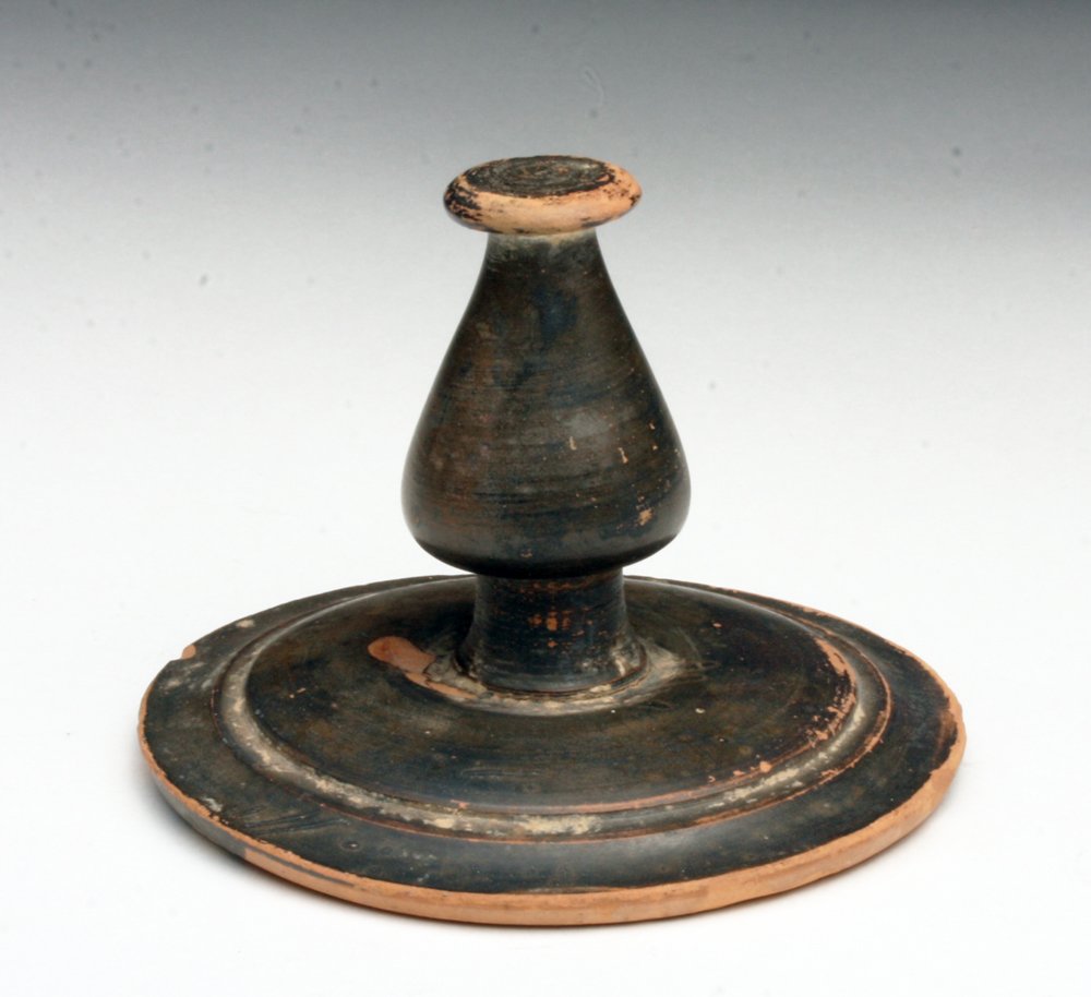 Signed Greek Blackware Jar Lid: Southern Italy, Ca 4th century BCE. Lid for a blackware vessel - probably a lebes gamikos, with large turned spool, signed on base looking like a Pi or F. 3-5/16" D x 2-1/2" H. If you have the right s
