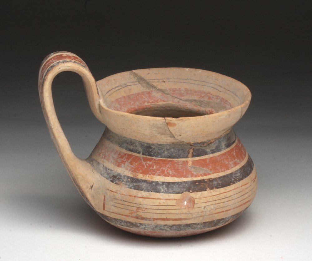 Cute Daunian Squat Pitcher: Southern Italy, 4th century BCE. A cute pottery olpe, decorated in alternating bands of red and black, with thin flared rim and squat round body, large handle connecting these. 4-1/8" H. Provenance: E