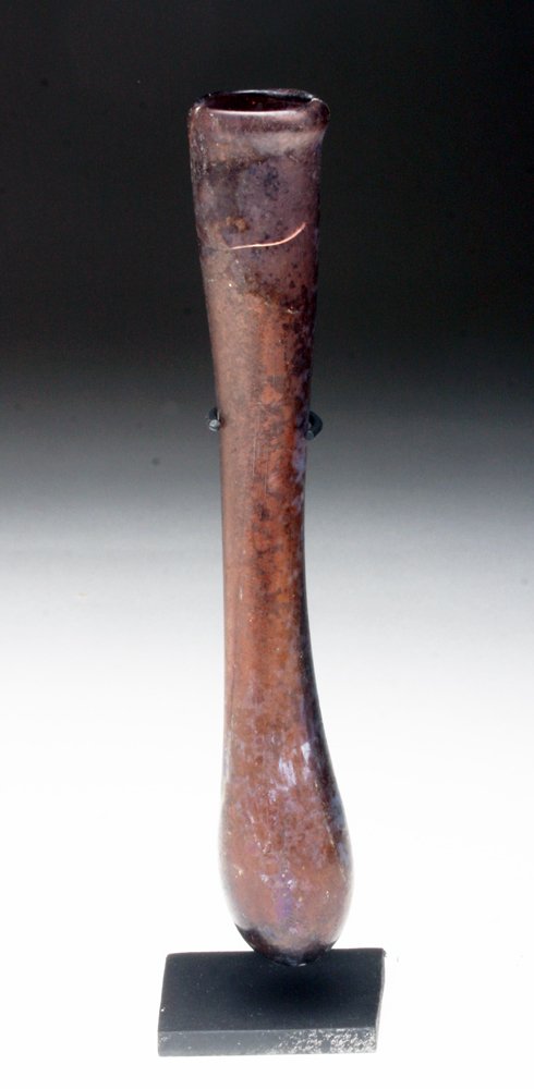 Roman Aubergeine Glass Vial: Roman Empire, Ca 1st century CE. Another stunning piece of glass in royal purple! Long vial, sometimes called a tear vial, but most likely used to hold precious oils and perfumes. Measuring a long 5-1