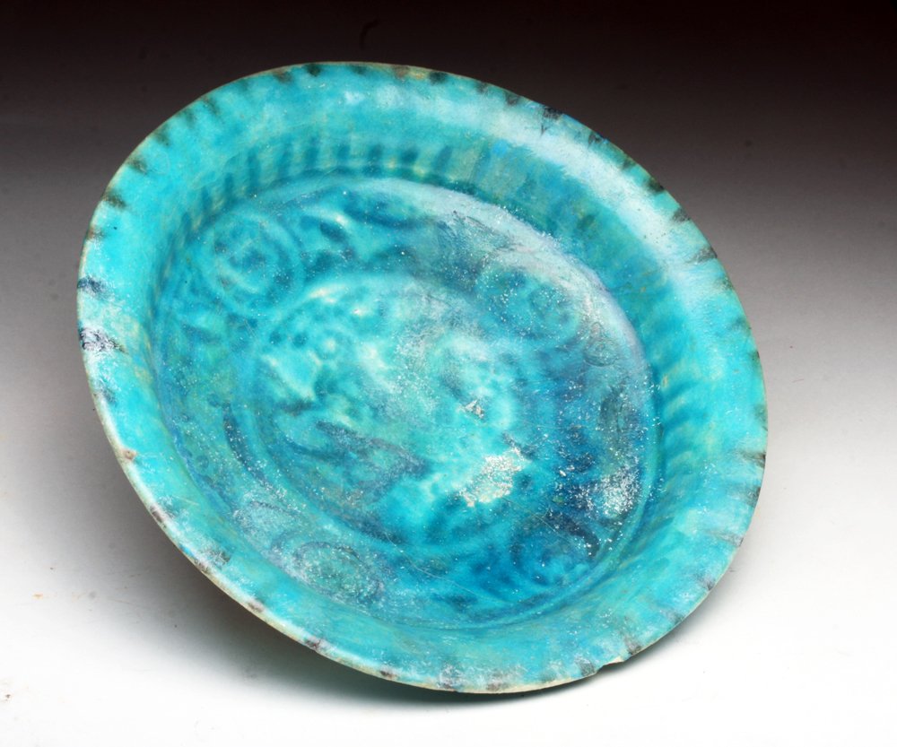 Islamic Blue Glazed Dish, possibly Kashan: Iran, Ca 12th to 14th century, possibly Kashan region. Another stunning sky blue ceramic plate impressed in the center with floral patterns. Areas of silvery iridescence! 6-3/4" D. Provenance: Ex-Smit