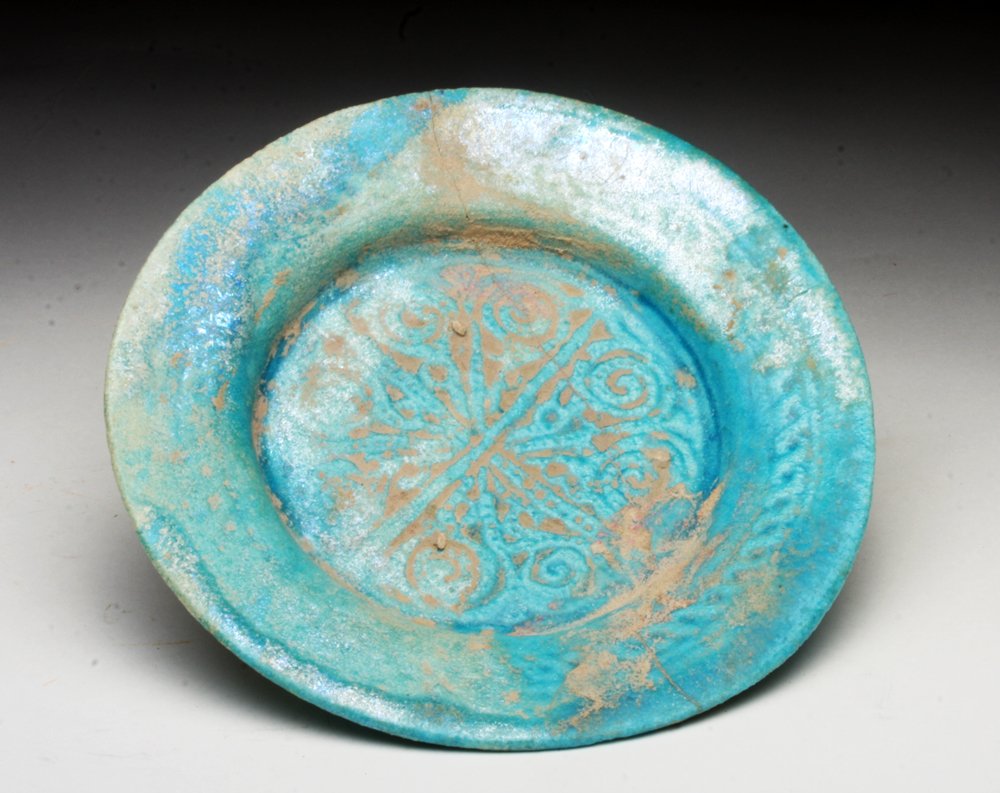 Another Islamic Blue Glazed Dish, possibly Kashan: Iran, Ca 12th to 14th century, possibly Kashan region. Stunning sky blue ceramic plate impressed in the center with floral pattern. Exquisite areas of silvery iridescence! 6-1/4" D. Provenance: Ex-Smi