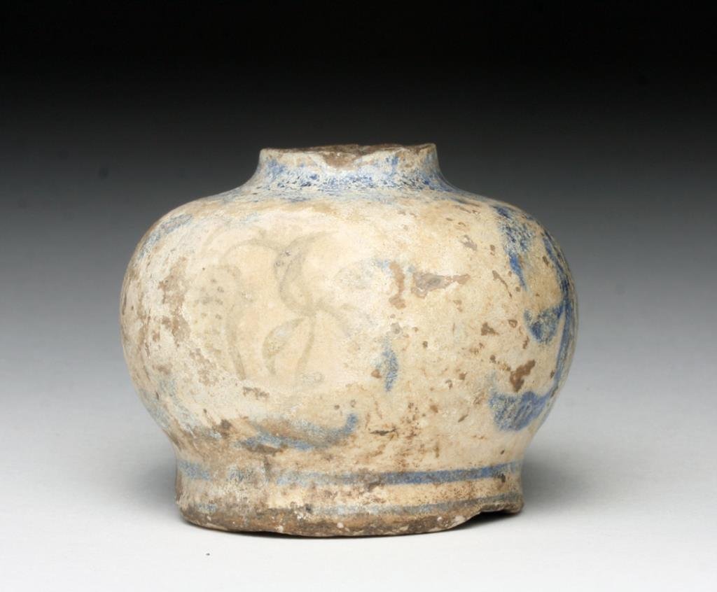Islamic Glazed Short Jar: Turkey/Iran, Ca 12th to 14th century. Another stunning example of Islamic Pottery! Short jar decorated with blue over white glaze in floral pattern, silvery iridescence throughout! 2" D by 1-3/4" H. P