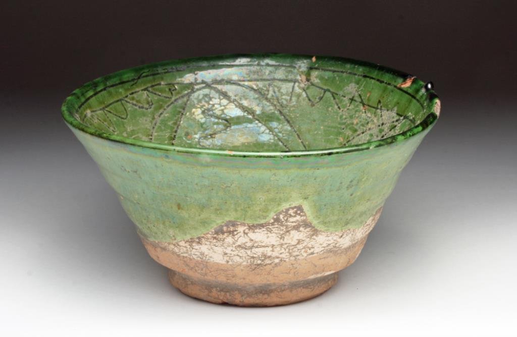 Islamic Green Glazed Incised Bowl: Central Asia, Ca 700 to 900 CE. Nishapur pottery bowl, with deep well, short foot, covered in green glaze and incised with cross-hatching and floral designs. A superb example! 6-1/2" D, 3-1/2" H. Prov