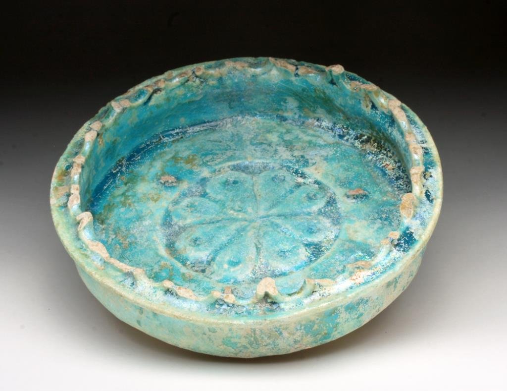 Stunning Islamic Kashan Blue Glazed Dish: Iran, 13th to 14th century. Deep blue glazed ceramic dish on short foot, straight walls, impressed floral design in center, edges of bowl once with repeating scalloped loops. Beautiful iridescent surf