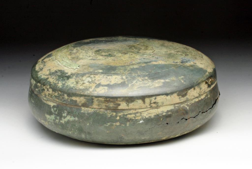 Rare Khmer Covered Bronze Box: Cambodia, Ca 12th to 14th centuries CE. Very rare to find! Two part bronze "box" in circular form. Base and lid of simple construction with incised band on lid, base completely reserved. 8-1/2" D by 3